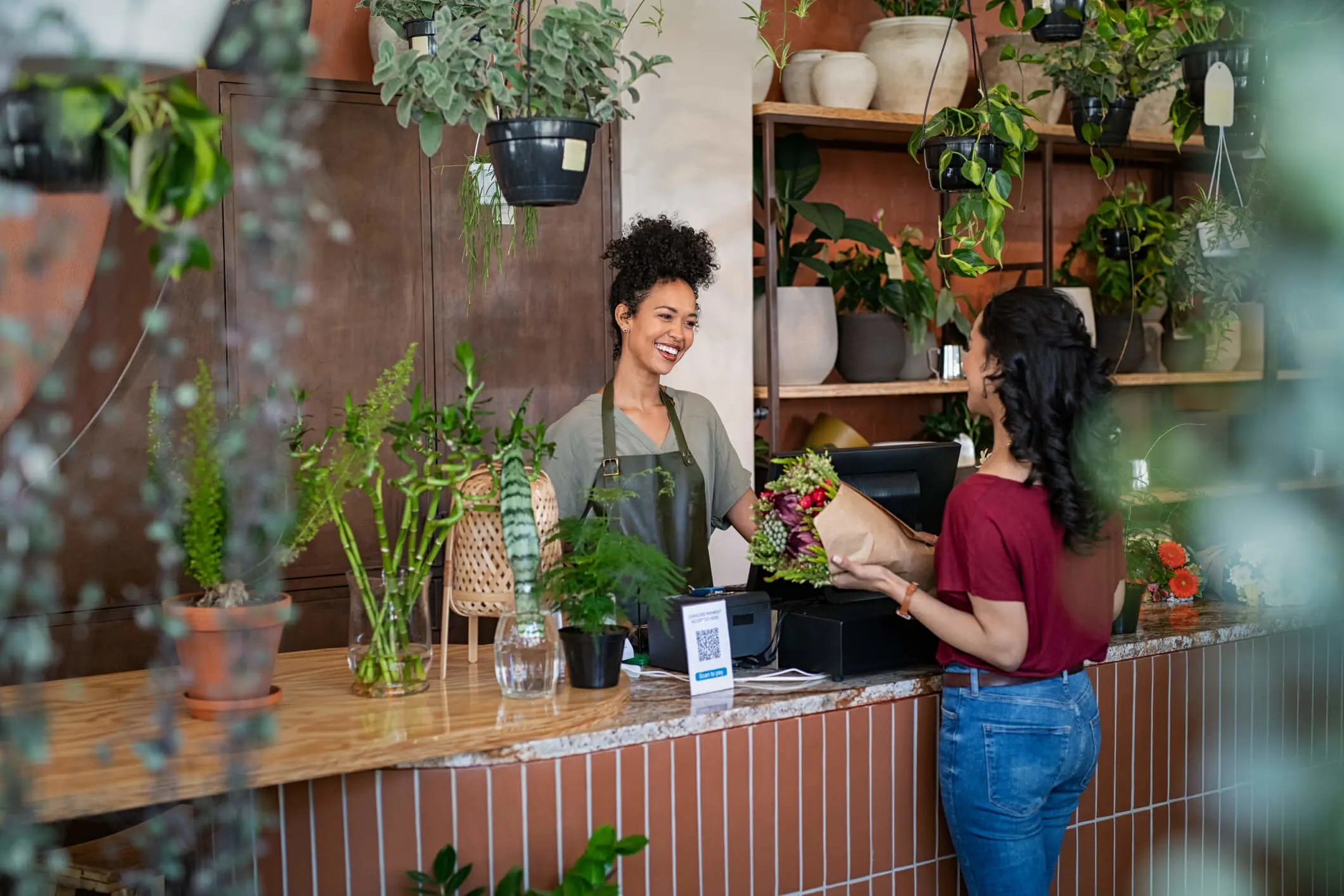 Een vrouw koopt een bos bloemen en heeft een babbeltje met de kassierster