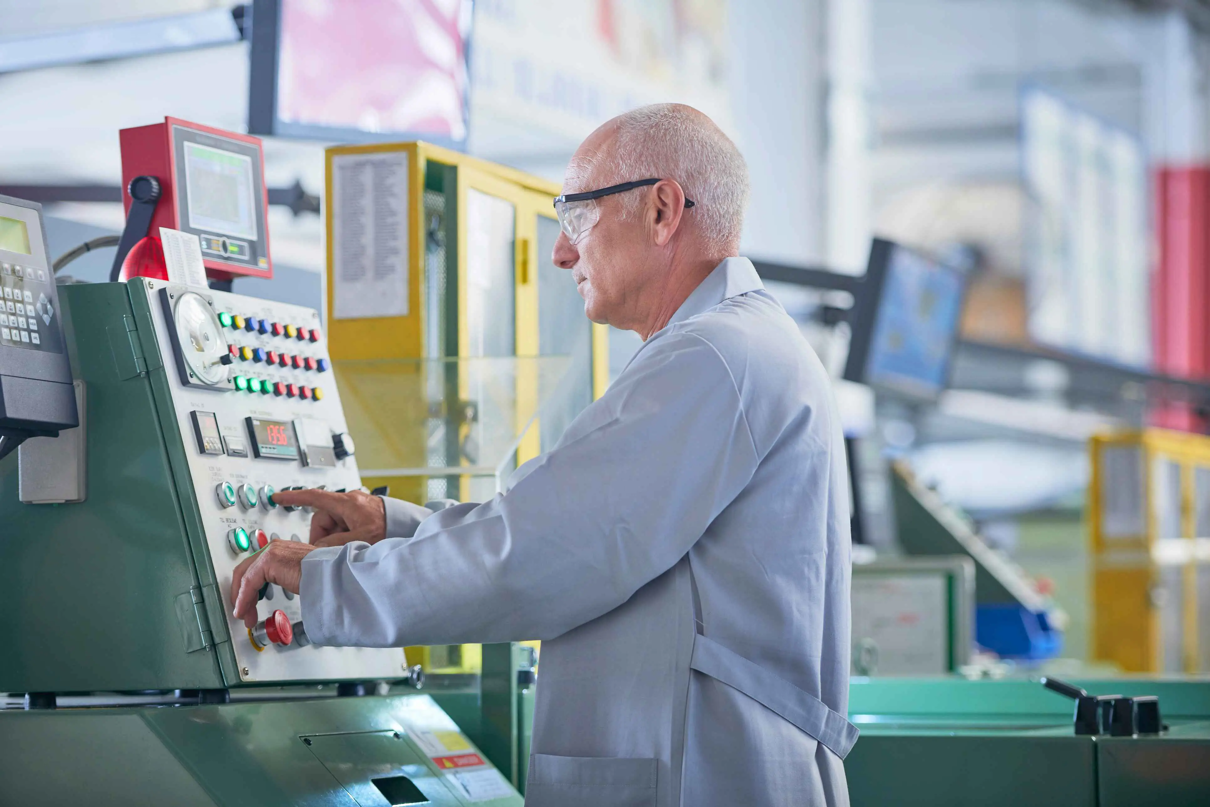 Oudere man met bril achter machine in fabriek