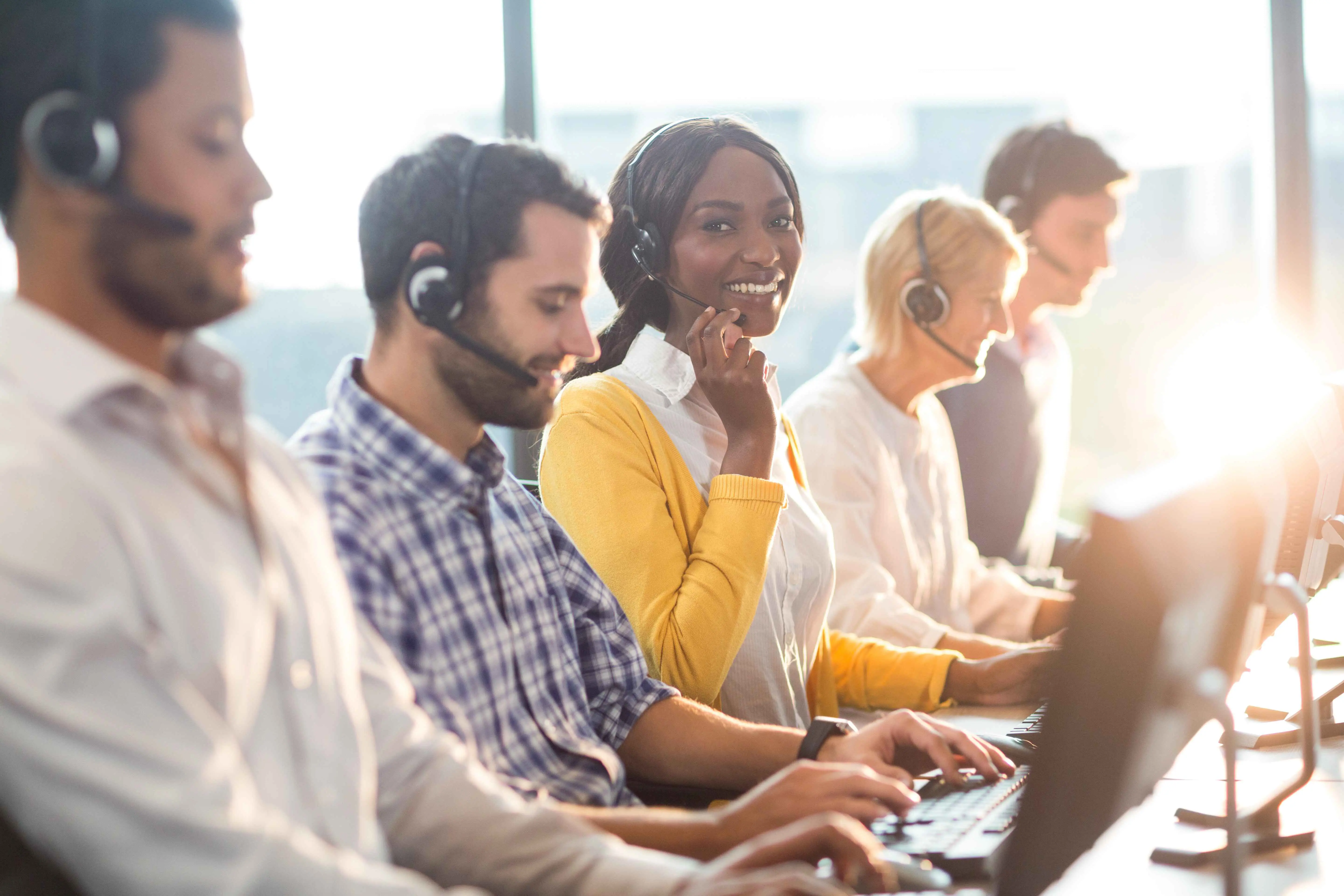 vier callcentermedewerkers die telefoons aan het beantwoorden zijn in een bureau